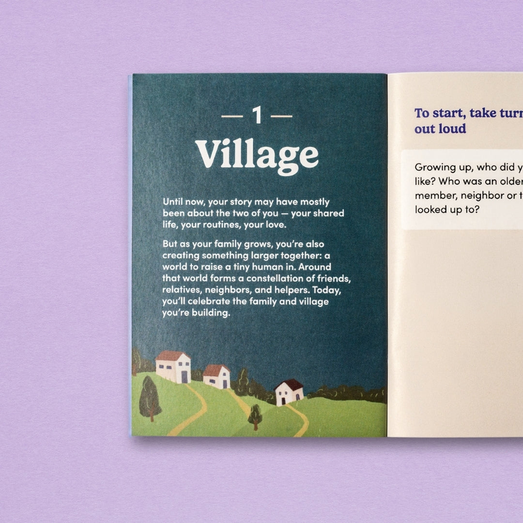 The guide booklet from It Takes a Village, open to the spread titled "Village", set on a lavender background. The left page is dark teal with the title "1: Village" and a small illustrated scene of houses and a winding road. The right page shows part of an instruction for this step.